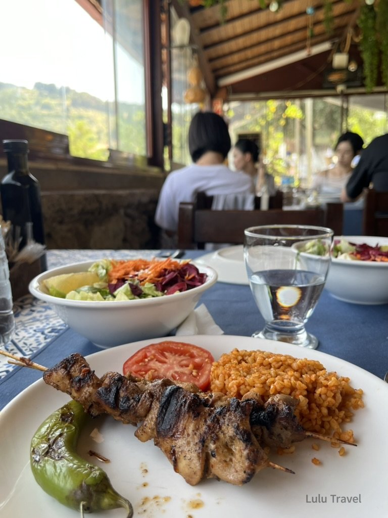 地道的土耳其烤雞肉串與布格麥飯（Bulgur）配新鮮生菜沙拉，擺放在色彩鮮豔的傳統地毯餐桌上。