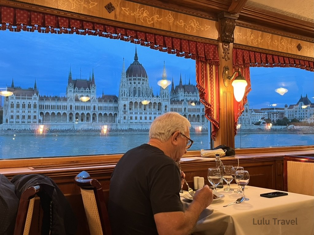 Traveling Europe with Elderly Family — Planning Logic and Honest Reflections 在布達佩斯多瑙河郵輪上用餐,窗外可見夜色中的匈牙利國會大廈