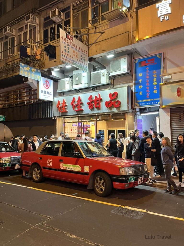 Hong Kong Trip Beyond the Surface: A Strategic 4-Day Itinerary 香港佐敦佳佳甜品門口夜景,紅色計程車停在路邊,排隊人潮等待甜品,展現香港夜晚的地道美食文化