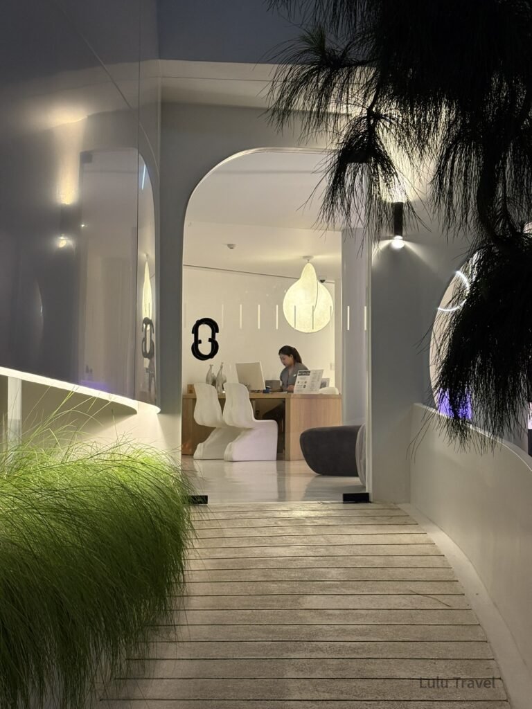 清邁 Chiang Mai 現代設計飯店接待空間，弧形建築與白色極簡室內設計，結合植栽與柔和燈光，呈現質感清邁住宿風格