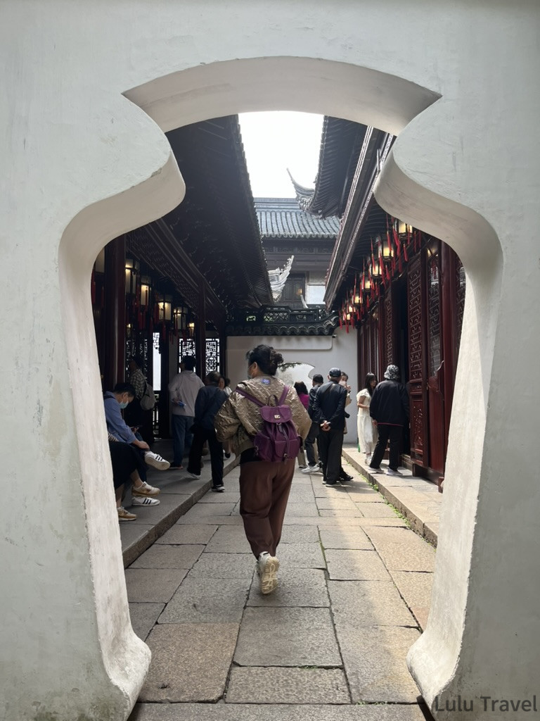 Shanghai City Walk — What I Got Wrong and What I'd Do Differently 上海豫園的傳統中式花瓶門框景觀,遊客漫步在鋪著石板路與古典木造建築圍繞的庭園走道中。