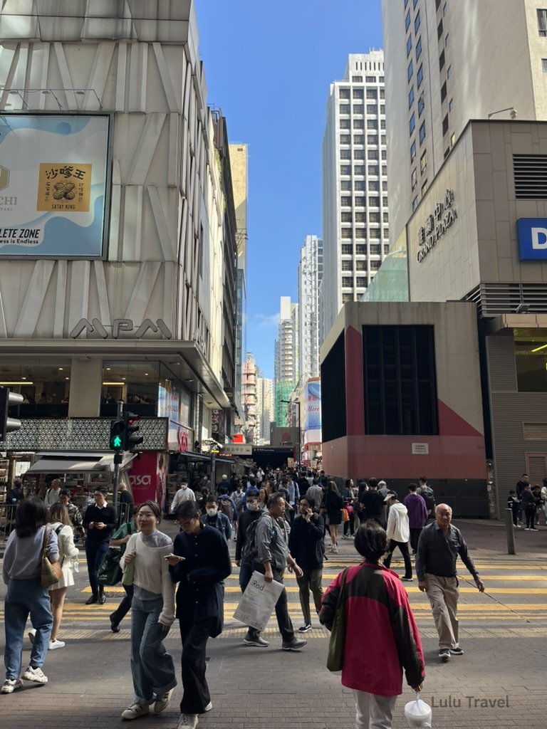 Hong Kong Trip Beyond the Surface: A Strategic 4-Day Itinerary 香港中環繁忙街景,行人穿越斑馬線,高樓林立的商業區呈現典型香港快節奏城市生活與街頭日常