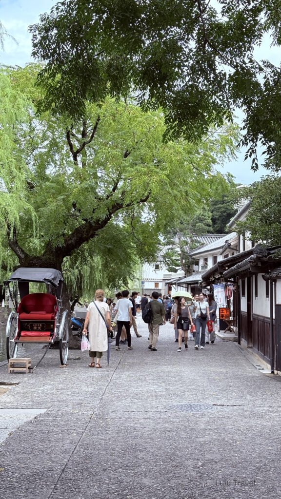 日本岡山倉敷美觀地區，傳統人力船行經石橋下，兩岸為白牆黑瓦的江戶時代街屋