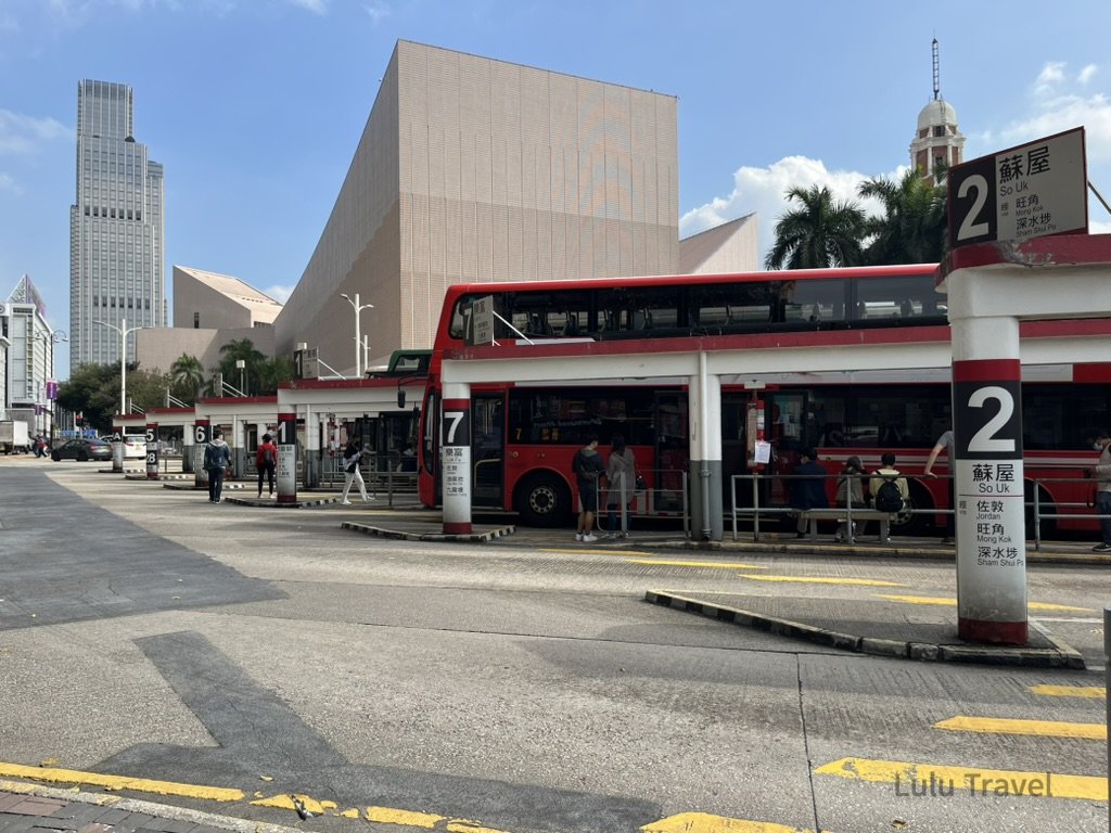 Hong Kong Trip Beyond the Surface: A Strategic 4-Day Itinerary 香港市區巴士總站實景,紅色雙層巴士停靠月台,背景可見現代建築與市中心街景,呈現香港旅遊行程第一站的交通與城市風貌