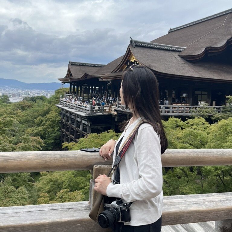 Travel Life Observations & Sharing 匈牙利布達佩斯漁夫堡觀景台,一名旅人倚靠石柱眺望多瑙河與對岸國會大廈,背景是布達佩斯城市天際線