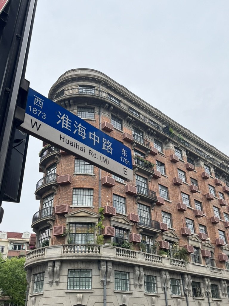 Shanghai City Walk — What I Got Wrong and What I'd Do Differently 上海淮海中路街口的租界時期紅磚弧形建築,外牆排列整齊的窗格與陽台,展現老上海城市立面