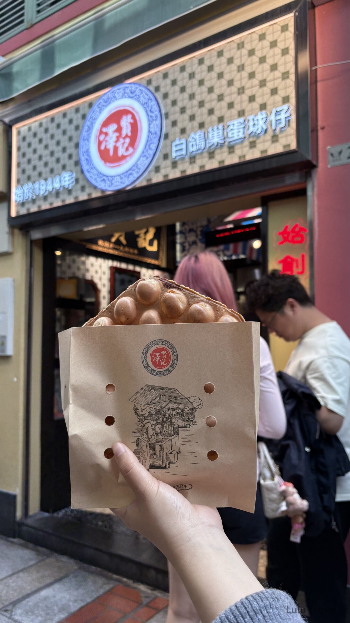 10+ Must-Eat Stalls in Macau: A No-Backtrack Food Route for 2 Days 1 Night 澳門必吃美食雞蛋仔,手拿熱騰騰的雞蛋仔站在澳門老字號小吃店門口,感受官也街周邊的人氣街頭美食文化