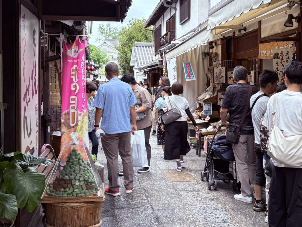 日本倉敷美觀地區商店街，人潮穿梭於保存完整的傳統街道與伴手禮店之間