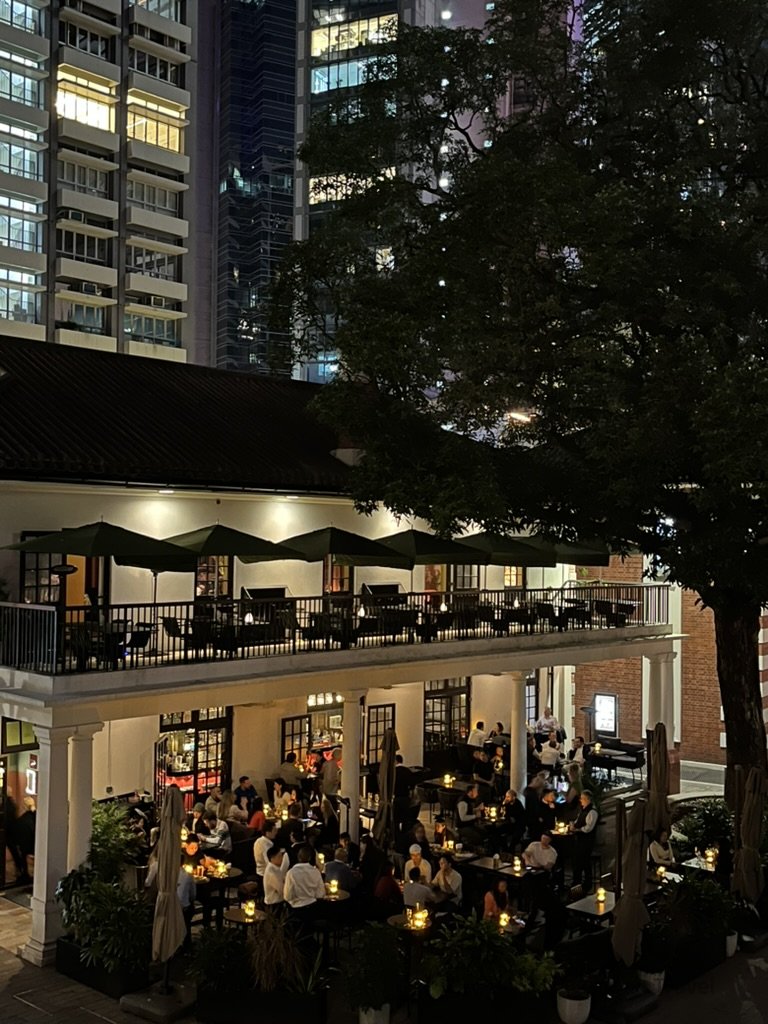 Hong Kong Trip Beyond the Surface: A Strategic 4-Day Itinerary 香港中環夜晚餐廳露台景色,戶外座位坐滿用餐人潮,背景為高樓林立的城市夜景,是下班後聚餐與旅遊推薦地點