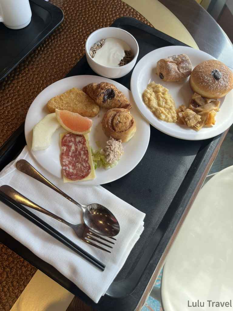 歌詩達郵輪自助式早餐餐點真實開箱，托盤內有麵包、薯餅、冷肉片與優格等常見菜色，重在吃飽。