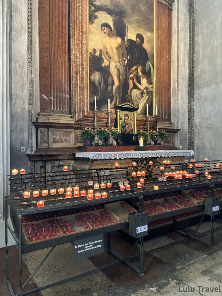 Salzburg Travel Guide — 5 Highlights and Why It's More Than a Mozart Stopover 薩爾斯堡主教座堂內部側廊,大型宗教畫作前排列著紅色祈禱蠟燭,燭火在昏暗空間中燃燒