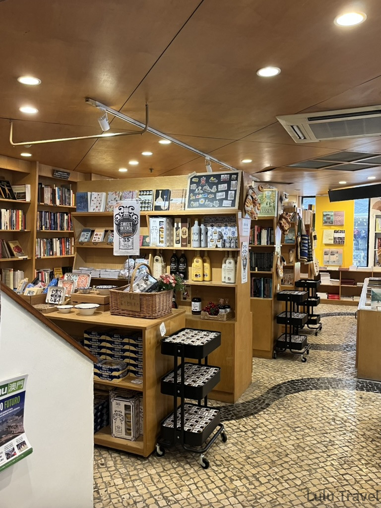 Accidental Macau Travel: A Spontaneous 2-Day Macau Self-Guided Itinerary 澳門葡文書局內部,木質書架陳列書籍與葡式食品,石板地面延伸至採光良好的書局深處