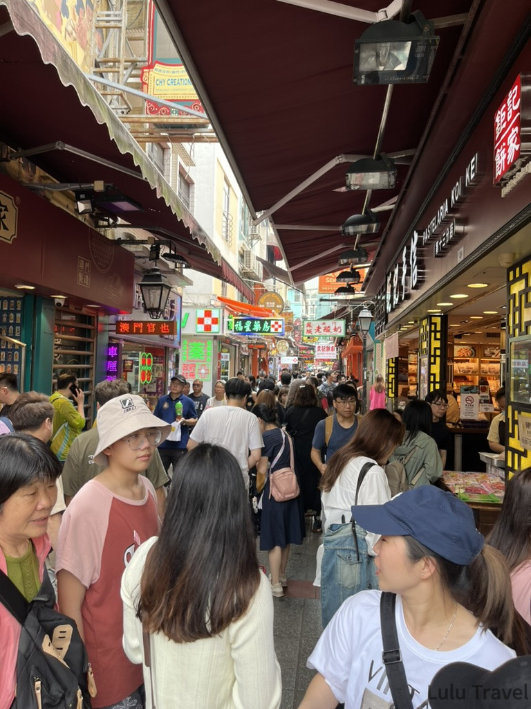 Accidental Macau Travel: A Spontaneous 2-Day Macau Self-Guided Itinerary 澳門官也街白天人潮,狹窄小吃街兩側密集排列各式澳門伴手禮攤位,旅客摩肩接踵