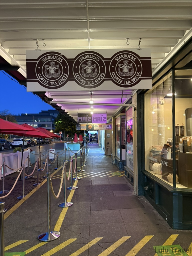 紐約行程規劃|DUMBO、百老匯、布魯克林到波士頓一日遊 西雅圖派克市場內的星巴克(Starbucks)創始店門面,懸掛著復古的棕色雙尾美人魚招牌,下方排隊動線清晰,呈現剛開店抵達時的安靜街景。