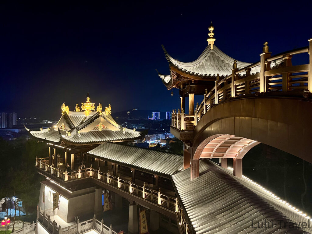 義烏雞鳴閣高處俯拍夜景，中式屋頂群與弧形迴廊錯落分布，遠方義烏市區燈火點綴夜空