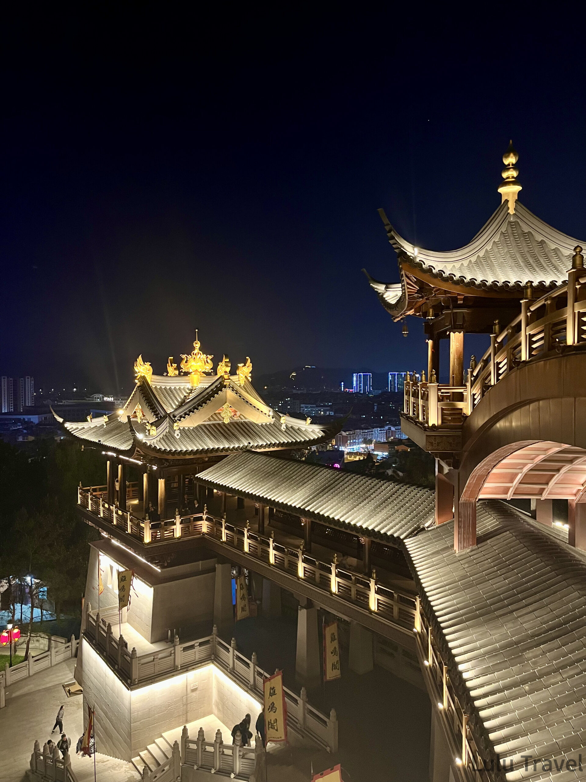 中國出差|深圳的震撼反差與義烏意外挖到的免費景點 義烏雞鳴閣夜間高角度全景,金色鳳凰雕飾屋頂與多層傳統建築群在燈光下清晰可見,背景為義烏城市夜景