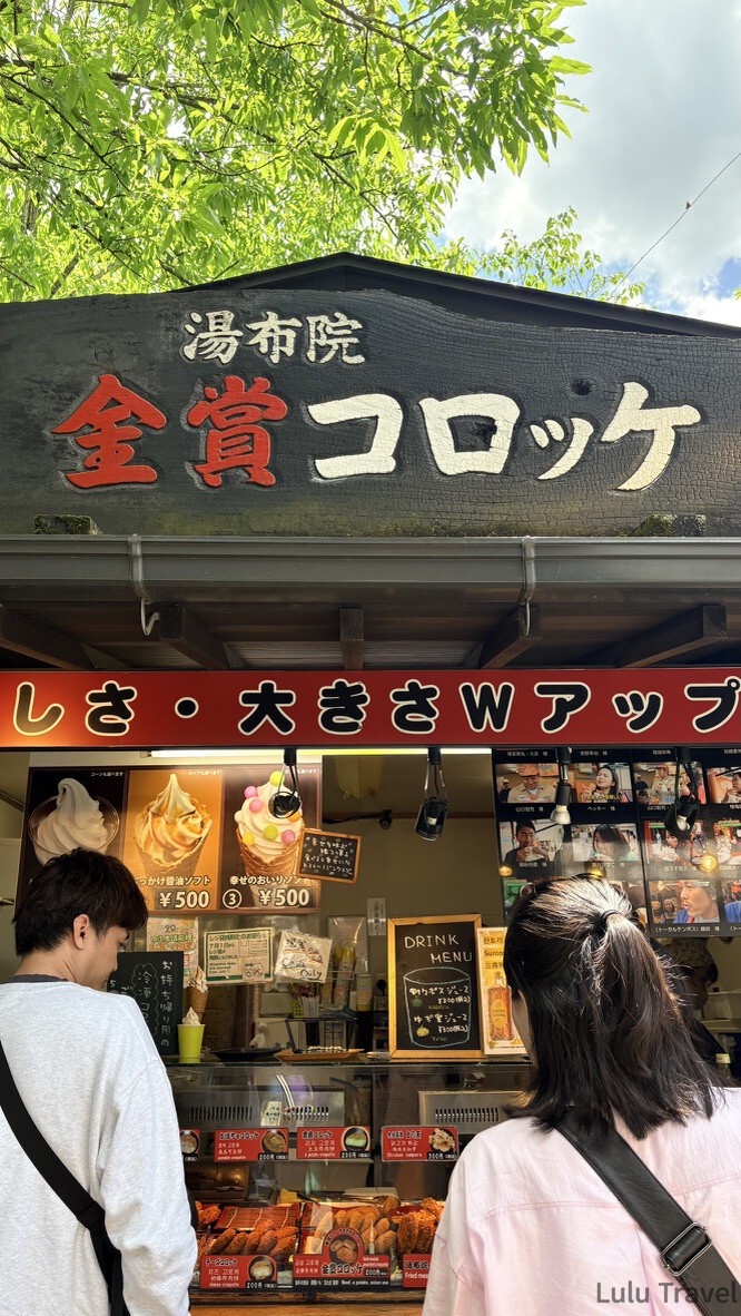 由布院兩天一夜|避開黃金週人潮的溫泉住宿與由布院之森 湯布院金賞可樂餅的店面,燒杉黑木招牌下的玻璃櫃與點餐人潮