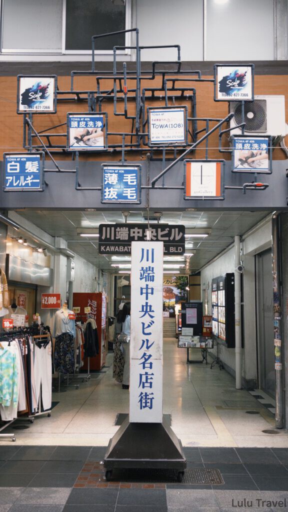 福岡自由行|日本黃金週的6 天 5 夜行程與消費明細 福岡博多川端通商店街的入口,立有川端中央大樓名店街的白色直立招牌,上方有著深色管線交錯的特色裝飾