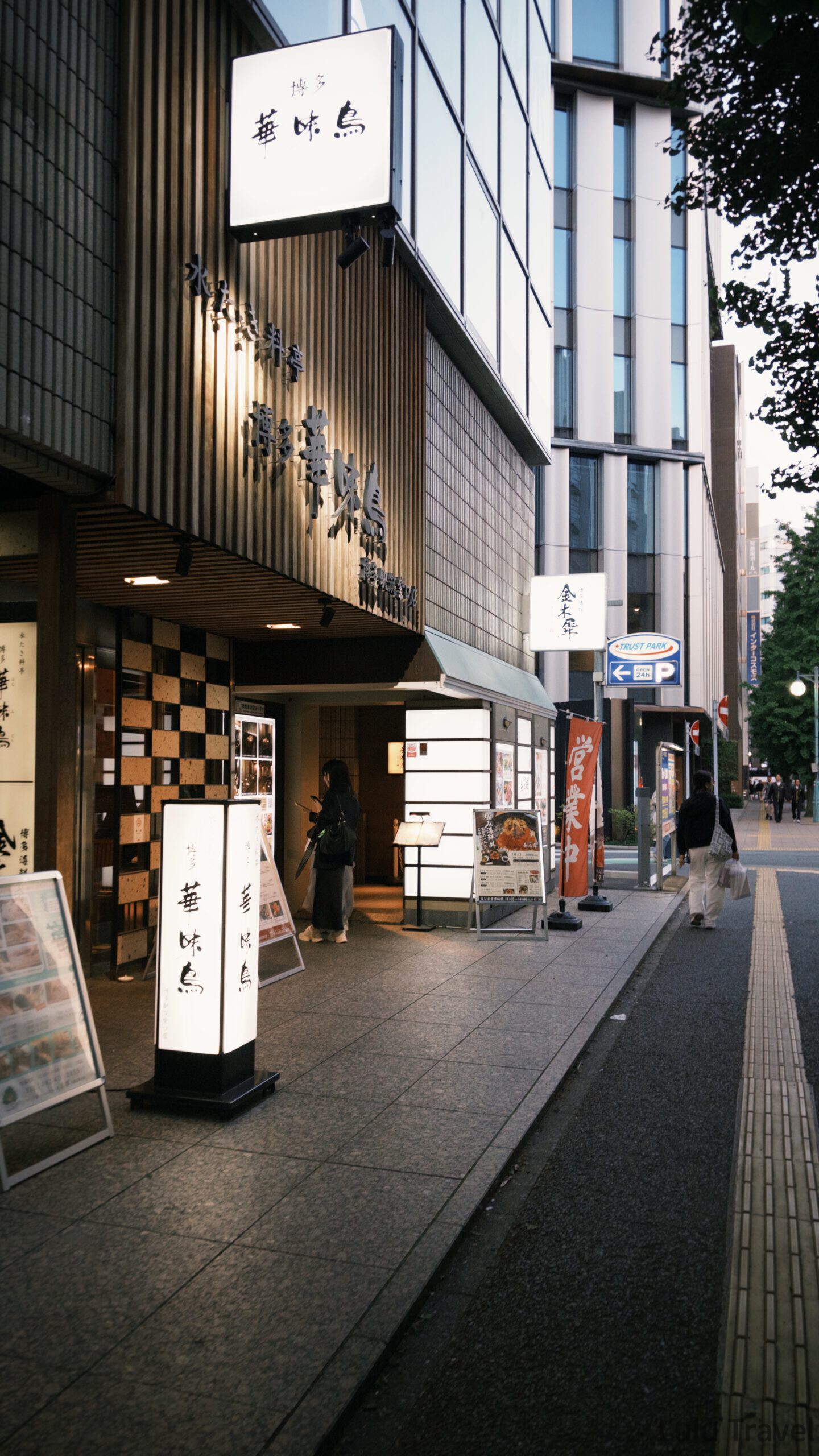 福岡自由行|日本黃金週的6 天 5 夜行程與消費明細 福岡博多市區的傍晚街景,知名水炊鍋餐廳「博多華味鳥」的店面外觀,騎樓下亮著白色的直立式招牌